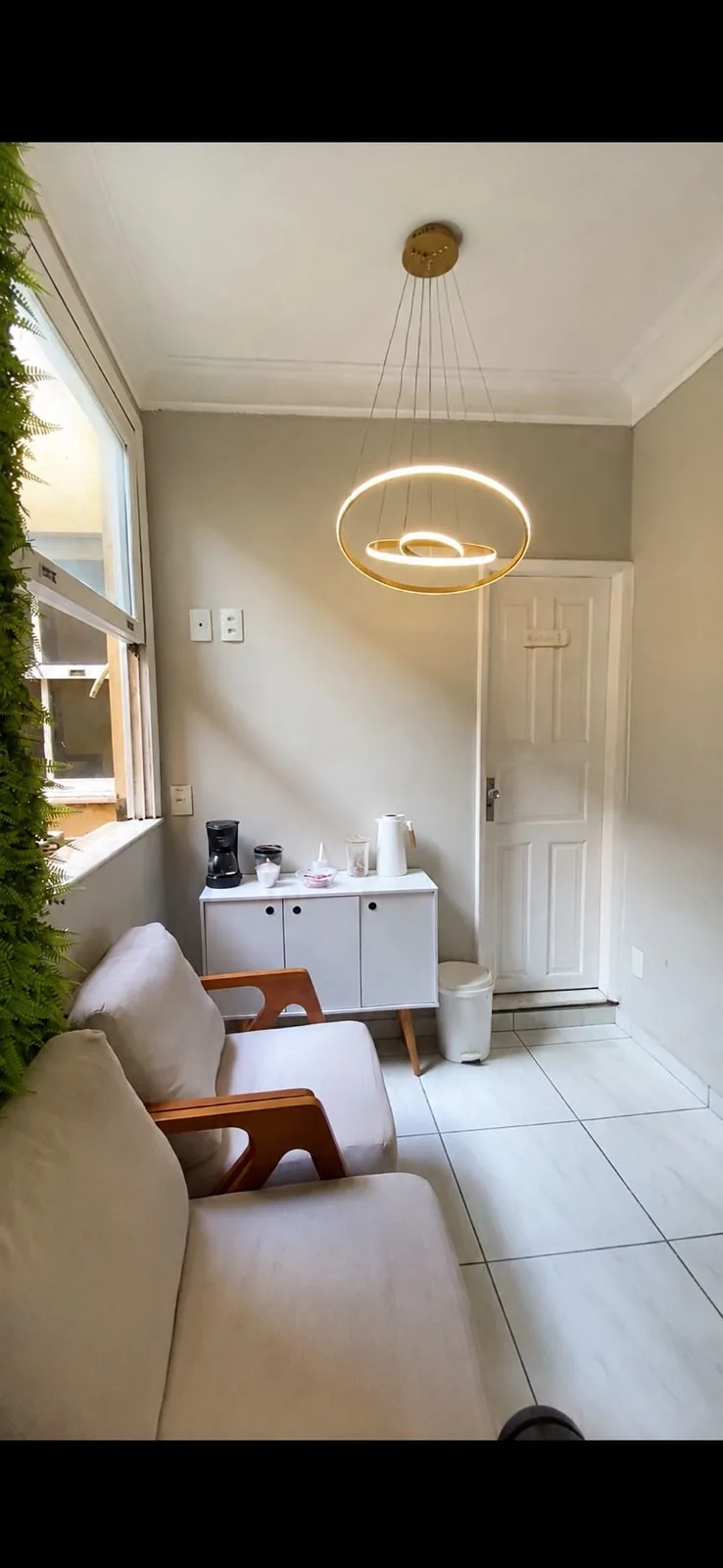 Studio Minali — sala de espera aconchegante com sofá bege e lustre dourado